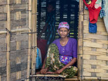 A woman poses for a photo while sitting in the opening of a doorframe.