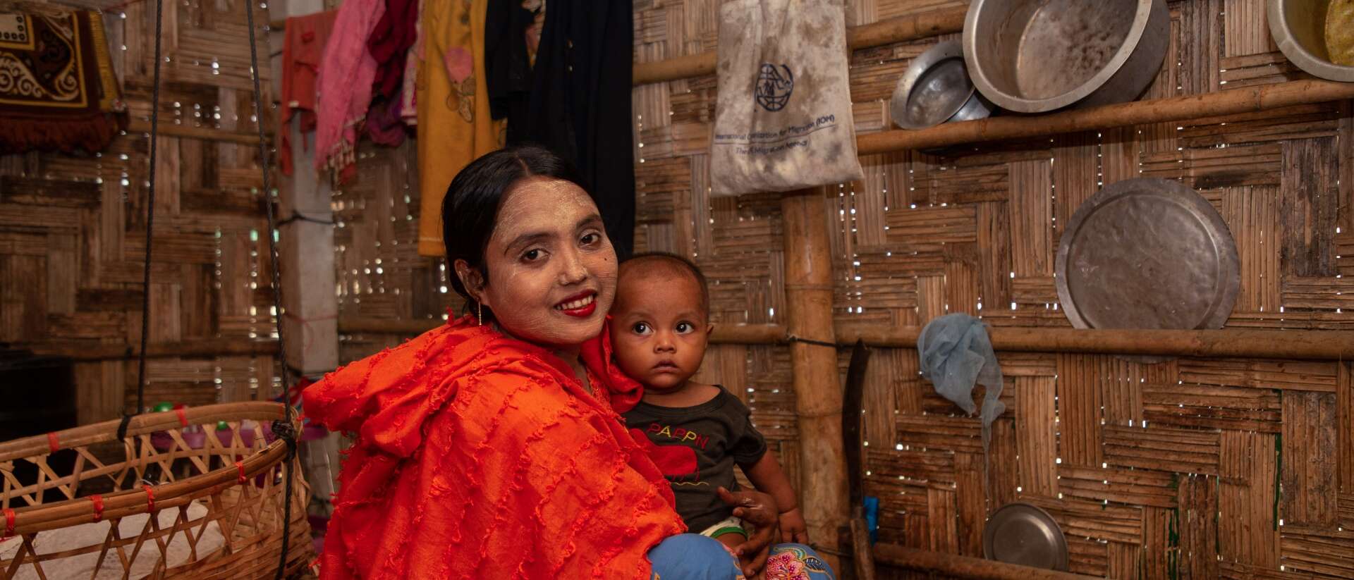 A mother holds her young child in her arms. Together, they pose for a photo.