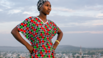 Lydia poses for a portrait on a hill above a city.